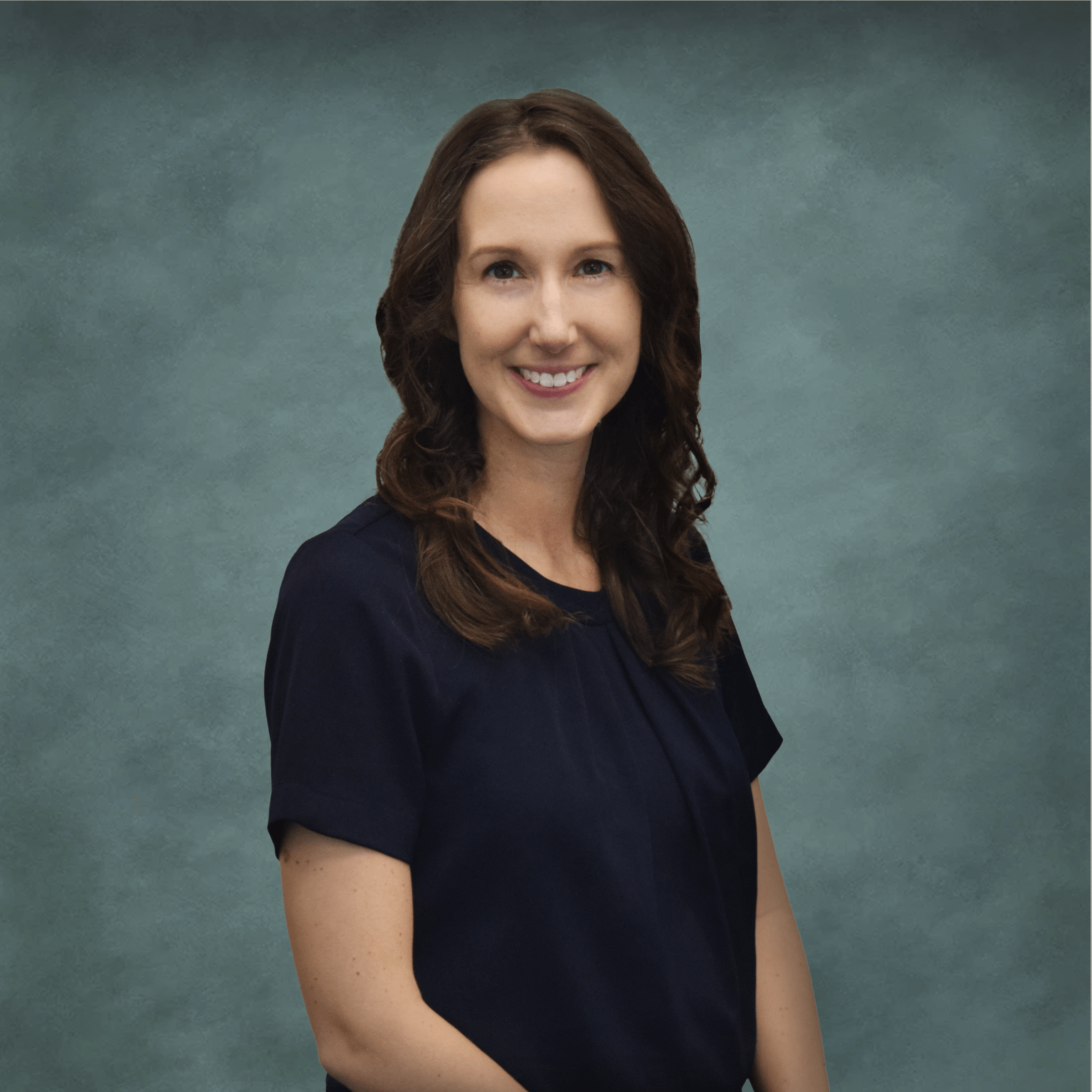 A professional headshot of Dr. Christine Shukis, an optometrist at Poudre Valley Eyecare, wearing a navy-blue blouse against a greenish-grey background.